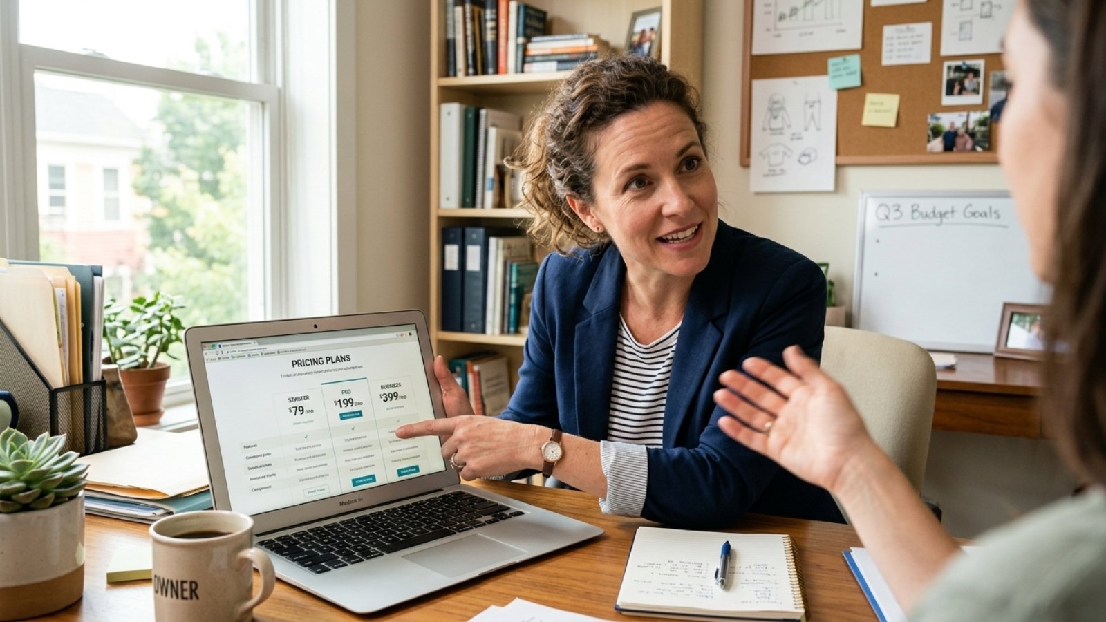 Small business owner reviewing website cost breakdown on a laptop while discussing pricing options